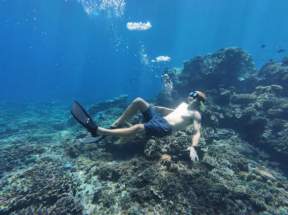 Roanin freediving, lying back over a coral reef with fins on