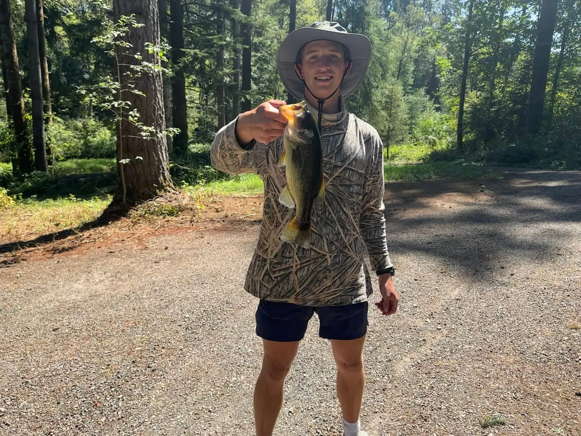Roanin in a bucket hat holding a largemouth bass