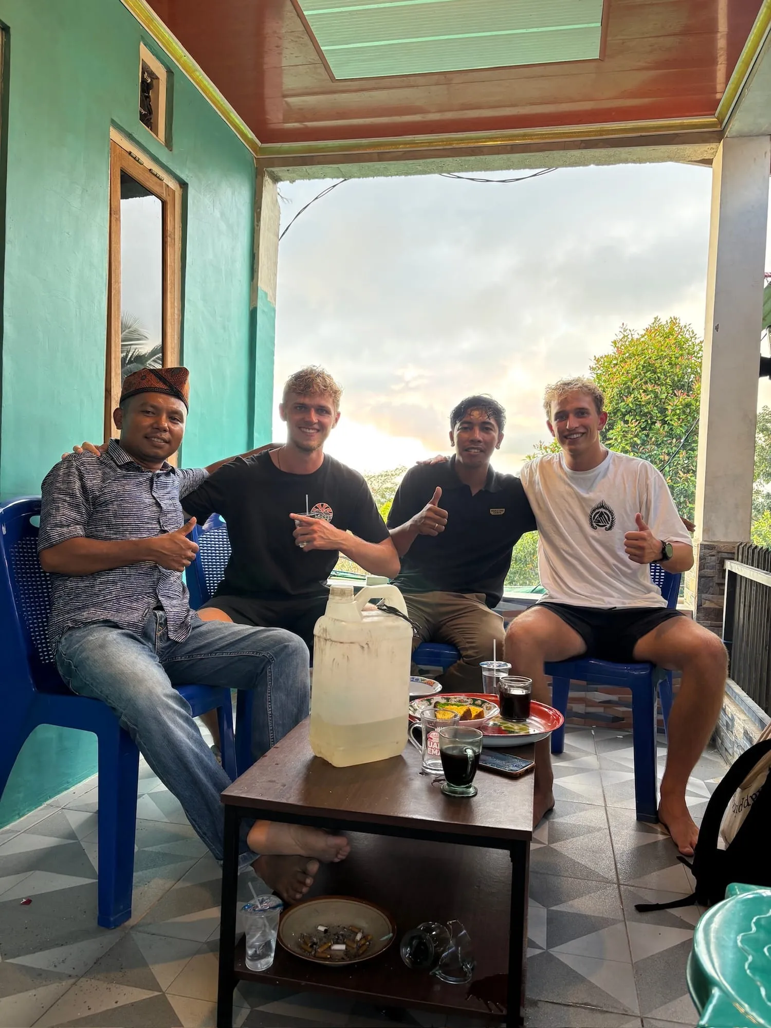 Roanin and three new friends on a porch in Flores, all giving thumbs up